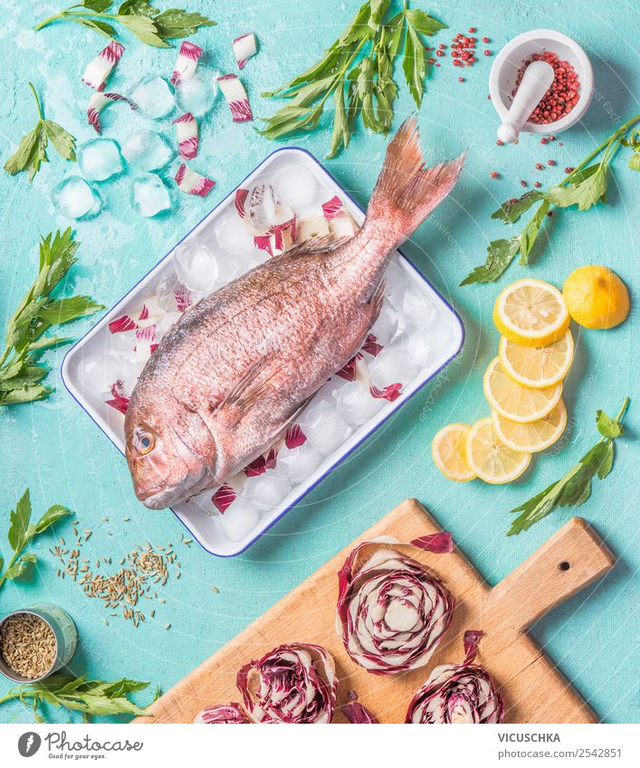 Dorado Fisch auf Küchentisch mit Zutaten Lebensmittel Kräuter & Gewürze Öl Ernährung Mittagessen Abendessen Bioprodukte Vegetarische Ernährung Diät Geschirr