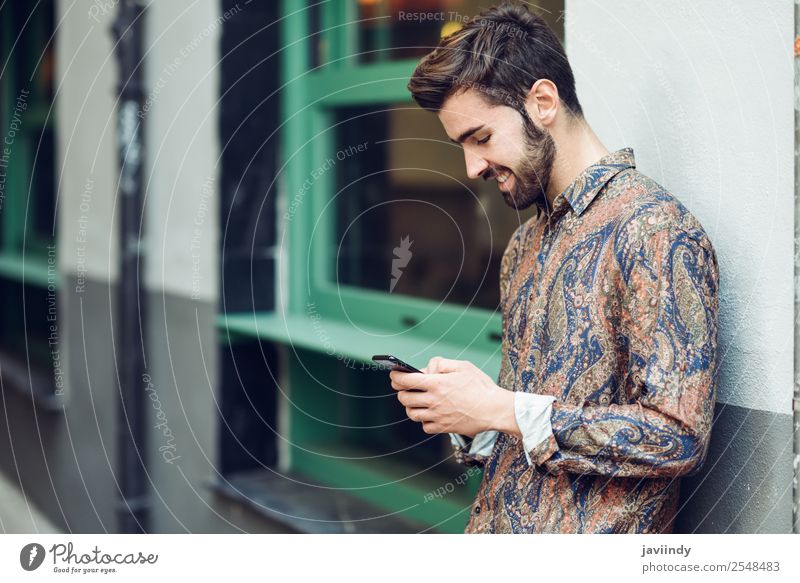 Junger lächelnder Mann schaut auf sein Smartphone auf der Straße. Lifestyle Stil schön Haare & Frisuren Telefon PDA Mensch maskulin Junger Mann Jugendliche