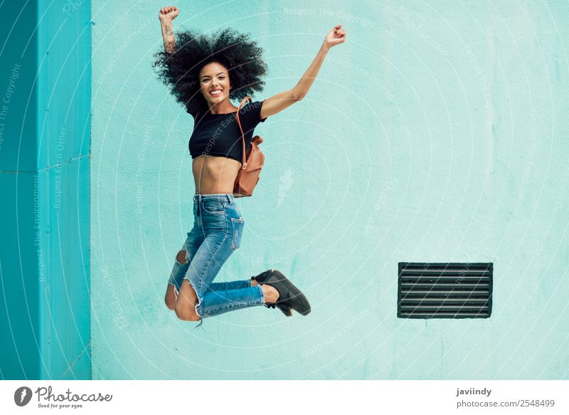 Junge gemischte Frau mit Afrohaar, die im Freien springt. Lifestyle Stil Glück Haare & Frisuren Gesicht Mensch feminin Junge Frau Jugendliche Erwachsene 1