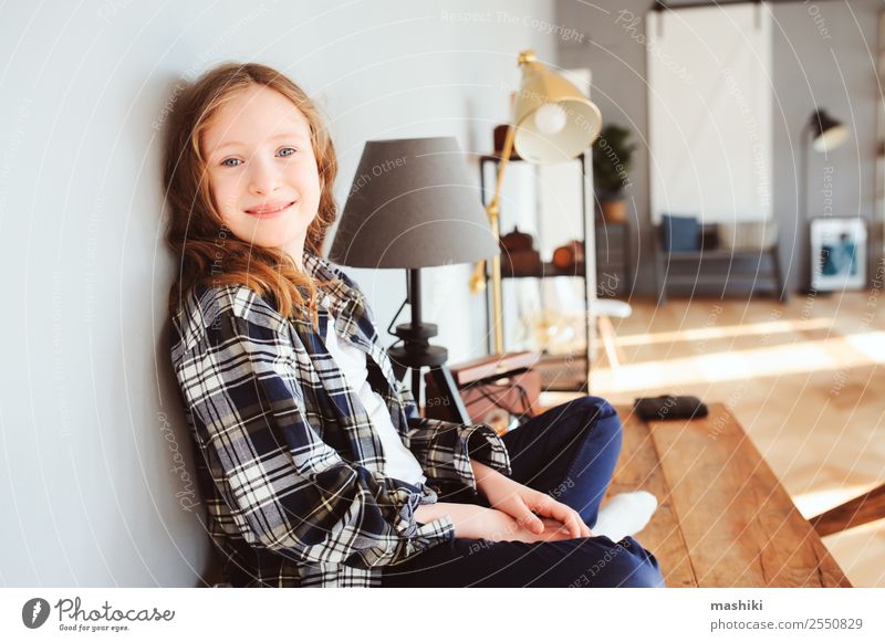 fröhliches Kind Mädchen sitzt auf dem Tisch zu Hause Lifestyle Erfolg Schule lernen Schulkind Kindheit Buch Schreibstift Lächeln schreiben sitzen klug Interesse