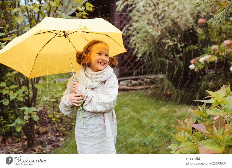 glückliches Kind Mädchen, das sich unter dem Regenschirm versteckt. Lifestyle Freude Glück Garten Kindheit Natur Herbst Wetter Park Pullover Tropfen lustig nass