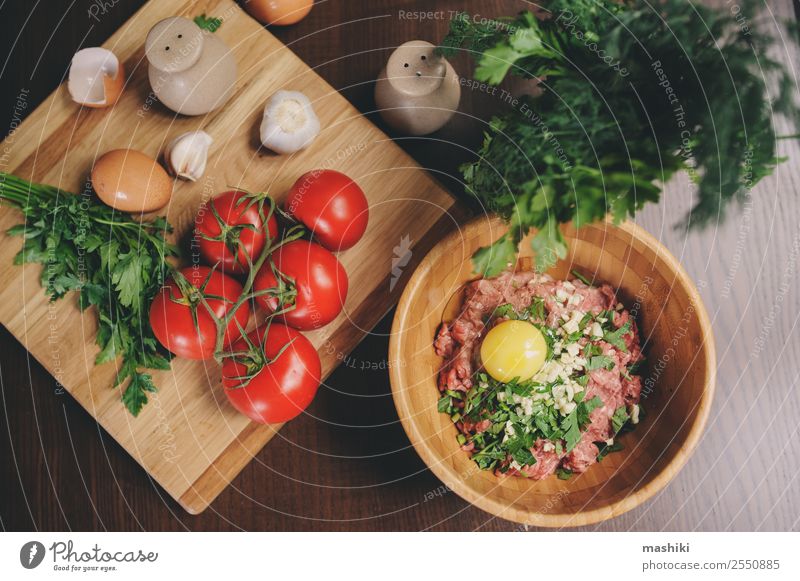 Rohes Hackfleisch mit Ei, Kräutern und frischen Tomaten Fleisch Gemüse Ernährung Teller Schalen & Schüsseln Küche Rindfleisch Ball Brotlaib vorbereiten