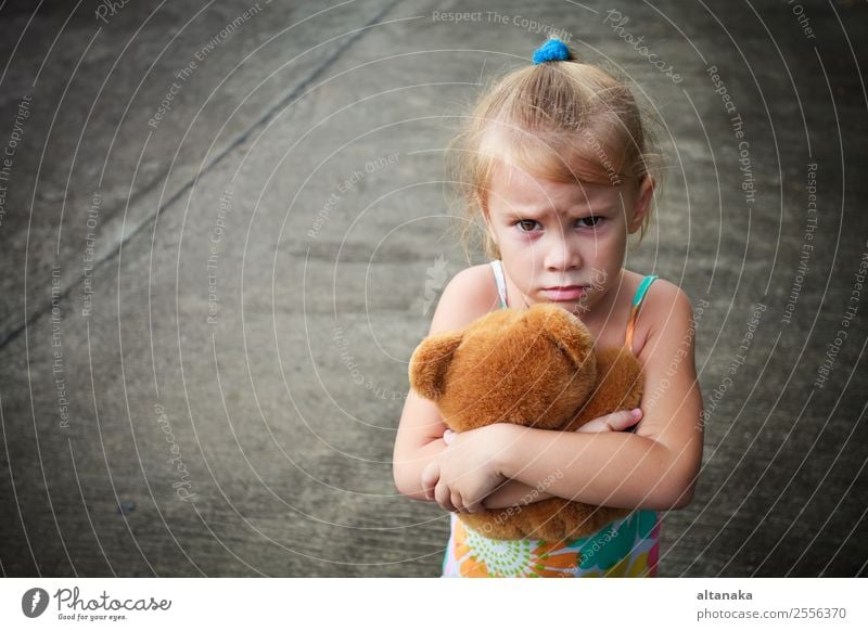 trauriges kleines Mädchen hält Spielzeug mit ihren Händen Gesicht Kind Mensch Frau Erwachsene Kindheit Straße blond Denken Traurigkeit niedlich Gefühle Sorge