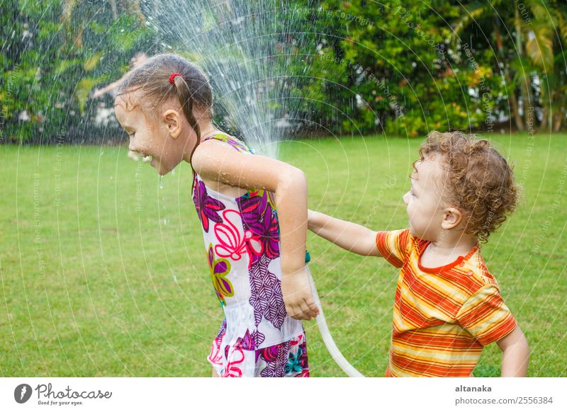 Der kleine Junge gießt ein Wasser aus einem Schlauch bei ihrer Schwester. Freude Glück Freizeit & Hobby Spielen Sommer Haus Garten Kind Mensch Mann Erwachsene