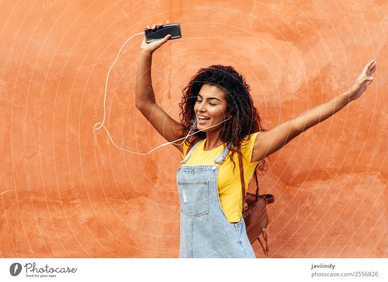 Glückliches arabisches Mädchen, das Musik hört und im Freien tanzt. Lifestyle Stil schön Haare & Frisuren Telefon PDA Technik & Technologie Mensch feminin