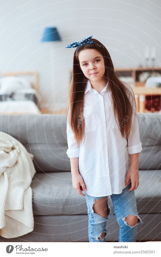 vertikales Porträt eines glücklichen 10 Jahre alten Mädchens zu Hause Lifestyle Stil Freude Erholung Wohnzimmer Kind Kindheit Mode Hemd Jeanshose Kleid Lächeln