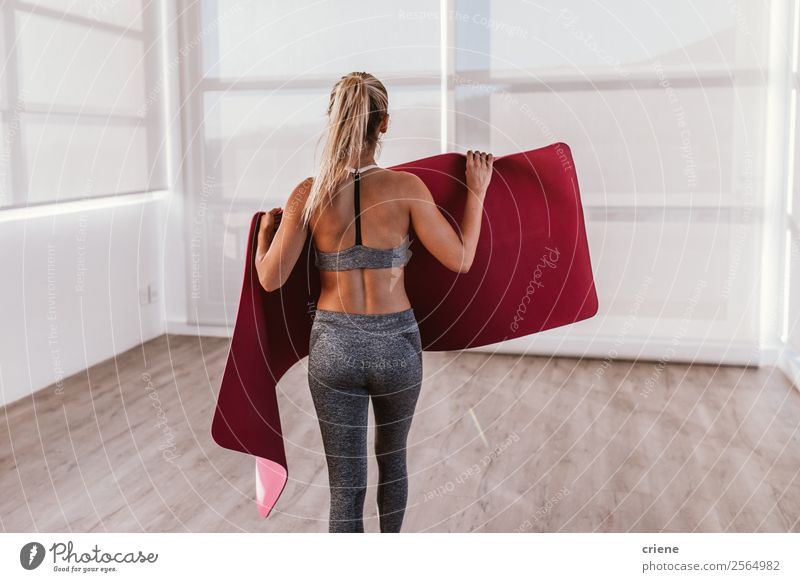 junge Frau, die eine Fitnessmatte für eine Übung vorbereitet. Lifestyle schön Körper Wellness Erholung Sport Yoga Mensch Erwachsene Band Unterwäsche Bewegung
