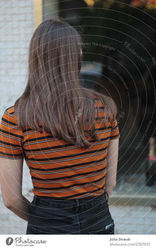 Schaufenster Frau schauen feminin Junge Frau Jugendliche 13-18 Jahre Stadt Stadtzentrum Fenster T-Shirt Hose brünett langhaarig Blick dünn schön retro orange