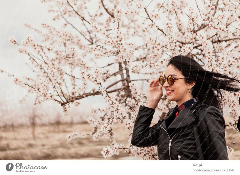 Mädchen Stil Glück schön Gesicht Garten Mensch Frau Erwachsene Natur Baum Blume Blüte Park Mode Jacke Leder Sonnenbrille brünett Lächeln Fröhlichkeit frisch