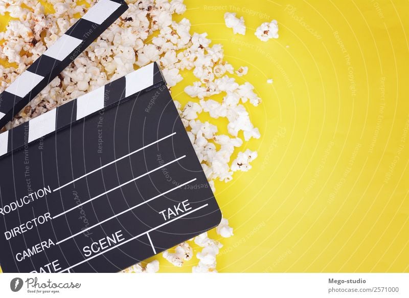 Popcorn und Klappe auf gelbem Hintergrund. Kinokonzept Fastfood Schalen & Schüsseln Freude Freizeit & Hobby Entertainment Industrie Theater Medien Fernsehen