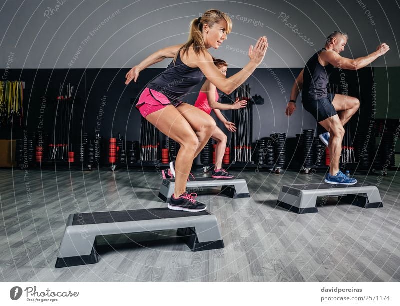 Frauentrainerin beim Aerobicunterricht mit Steppern im Fitnessstudio Lifestyle Glück schön Sport Mensch Erwachsene Mann Freundschaft Menschengruppe springen