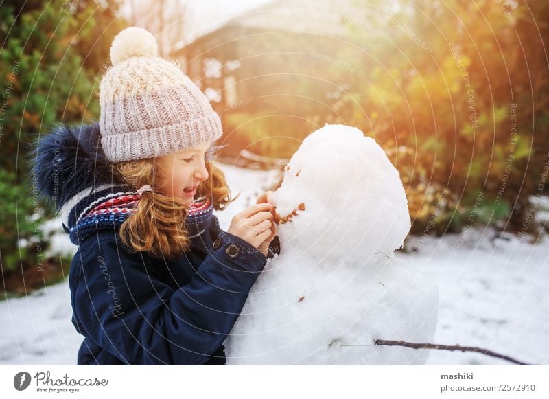glückliches Kind Mädchen macht Schneemann in den Weihnachtsferien Freude Freizeit & Hobby Spielen Ferien & Urlaub & Reisen Winter Winterurlaub Garten Natur