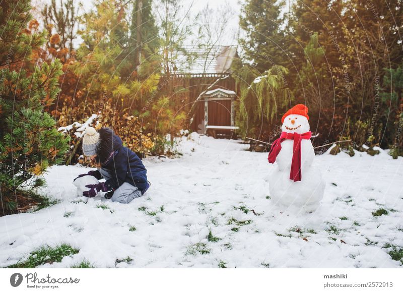 glückliches Kind Mädchen macht Schneemann an Weihnachten Freude Freizeit & Hobby Spielen Ferien & Urlaub & Reisen Winter Garten Natur Wetter Park Bekleidung