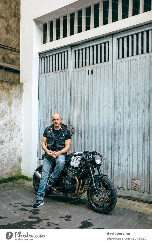 Biker posieren mit einem Motorrad Lifestyle Stil Ausflug Mensch Mann Erwachsene Straße Fahrzeug Glatze sitzen authentisch retro schwarz Stolz benutzerdefiniert