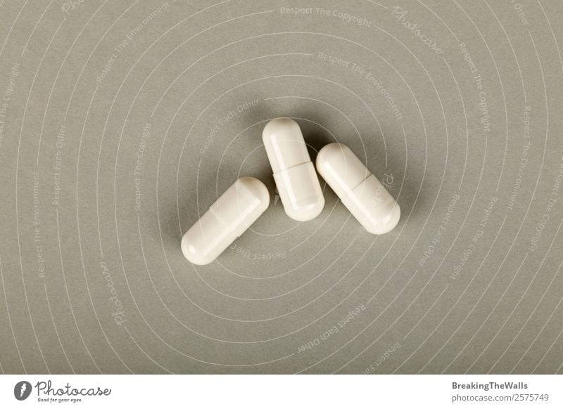 Nahaufnahme von drei weißen Gel-Cap-Pillen der Medizin über grauem Hintergrund Gesundheit Gesundheitswesen Behandlung Gesunde Ernährung Krankheit Rauschmittel