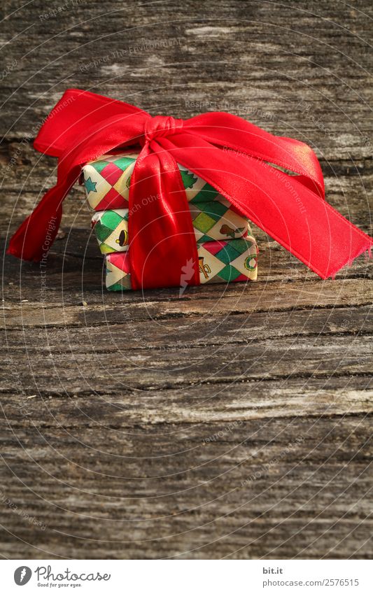 Überraschung l bunte Weihnachtspäckchen verpackt mit Weihnachtspapier mit roter Schleife, liegen auf rustikalem Holz. Weihnachtsgeschenke, liegen hübsch dekoriert mit Band auf Holztisch. Viele Weihnachtspäckchen mit Geschenkpapier mit Weihnachtsmotiv.