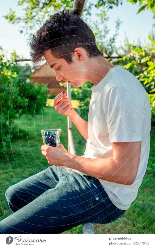 Teenager Junge genießt es, die frischen Heidelbeeren im Freien zu essen. Lebensmittel Frucht Ernährung Essen Bioprodukte Vegetarische Ernährung Diät