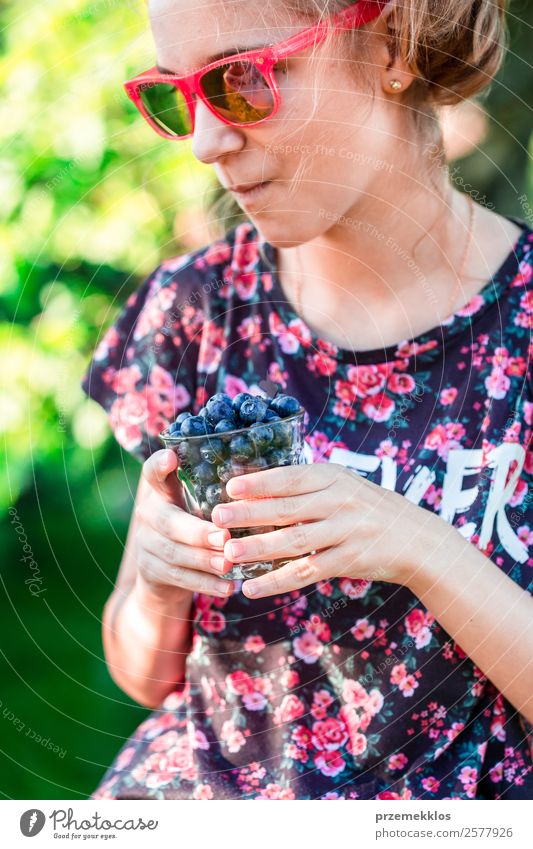 Glückliches Mädchen genießt das Essen der frischen Heidelbeeren. Lebensmittel Frucht Ernährung Vegetarische Ernährung Diät Glas Lifestyle Sommer Garten Mensch