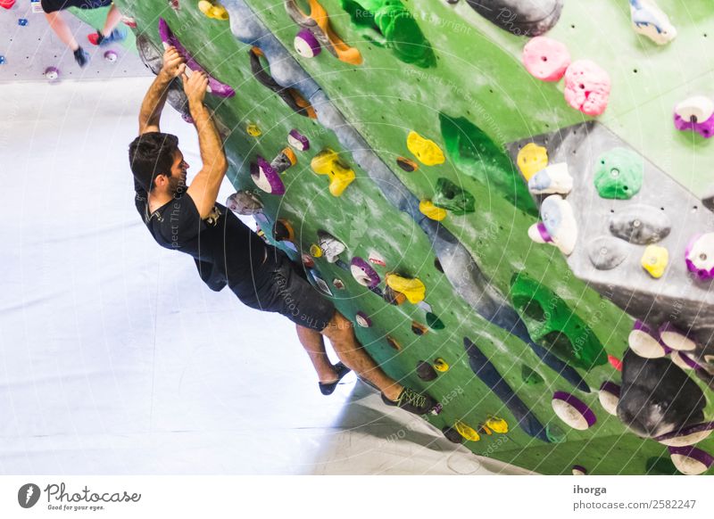 Ein Mann übt das Klettern an einer künstlichen Wand in Innenräumen. Lifestyle Freude Freizeit & Hobby Sport Bergsteigen Junger Mann Jugendliche Erwachsene Hand