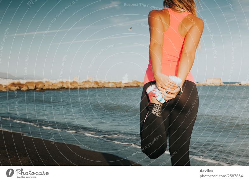 Sportlerin, die am Strand die Beine streckt, mit dem Meer im Hintergrund. Lifestyle Körper Sommer Fitness Sport-Training Joggen Mensch feminin Junge Frau