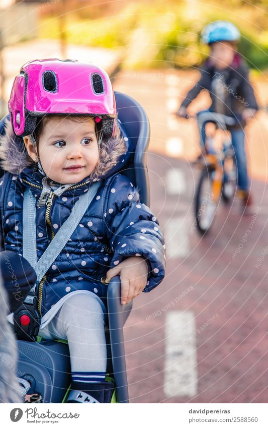 Kleines Mädchen mit Helm auf dem Kopf im Fahrradsattel sitzend Lifestyle Freizeit & Hobby Ferien & Urlaub & Reisen Ausflug Winter Stuhl Kind Baby Kleinkind Frau