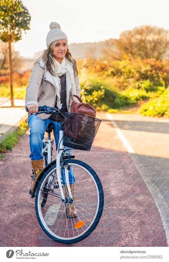 Junge Frau sitzt über dem Fahrrad auf einem Straßenradweg. Lifestyle Glück schön Erholung Freizeit & Hobby Sonne Winter Sport Fahrradfahren Mensch Erwachsene