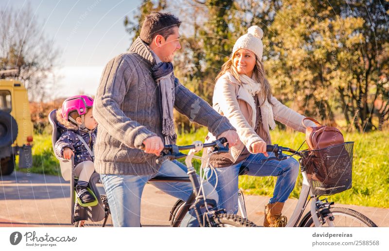 Familie mit kleiner Tochter, die auf einem Fahrradsattel sitzt und Fahrräder fährt. Lifestyle Glück Erholung Freizeit & Hobby Ferien & Urlaub & Reisen Sonne