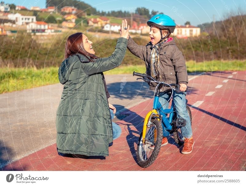 Mutter und Sohn, die fünf Personen geben, lernen Fahrrad zu fahren. Lifestyle Freude Glück Freizeit & Hobby Spielen Sonne Winter Sport Erfolg Fahrradfahren Kind