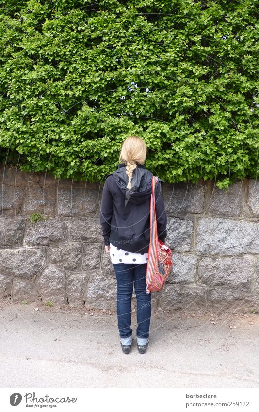 warten Junge Frau Jugendliche 18-30 Jahre Erwachsene Natur Schönes Wetter Sträucher Garten Mauer Wand Straße Wege & Pfade Tasche blond Zopf Stein stehen grau