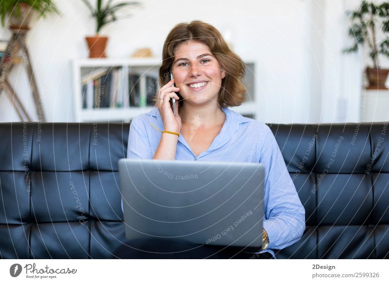 Unternehmerin im blauen Hemd bei der Arbeit mit einem Laptop, die zu Hause auf einer Couch sitzt kaufen Glück schön Sofa Schule lernen Studium