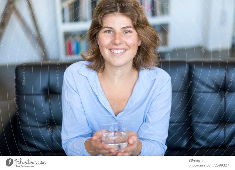 Frontalansicht Porträt eines glücklichen Teenagers mit einem Glas Wasser. Diät Getränk trinken Lifestyle Glück schön Gesicht Wellness Leben Sofa Fotokamera