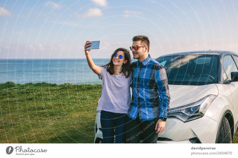 Junges Paar fährt Auto, Beifahrer benutzt Smartphone, lizenzfreies Stockfoto