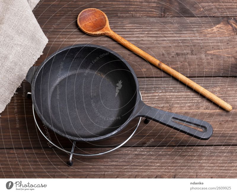 schwarze runde Gusspfanne aus Gusseisen Frühstück Abendessen Pfanne Löffel Küche Restaurant Metall Stahl stehen retro braun heimwärts leer Essen zubereiten