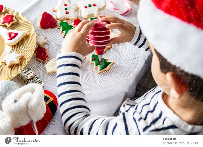 Kleines Kind schmückt Weihnachtsgebäck am Weihnachtstag Teigwaren Backwaren Dessert Süßwaren Freude Glück Freizeit & Hobby Dekoration & Verzierung Tisch Küche