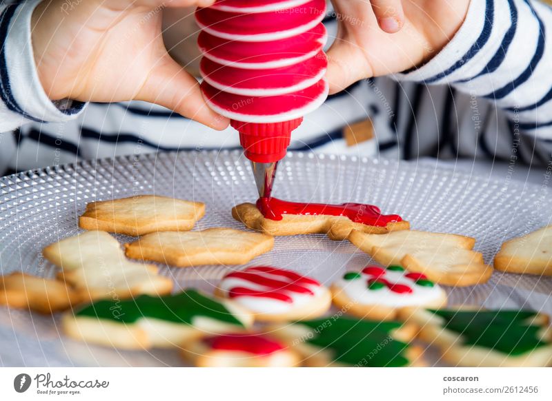 Kleines Kind schmückt Weihnachtsgebäck am Weihnachtstag Teigwaren Backwaren Dessert Süßwaren Freude Glück Dekoration & Verzierung Tisch Küche Feste & Feiern