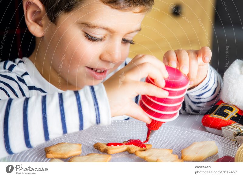 Kleines Kind schmückt Weihnachtsgebäck am Weihnachtstag Teigwaren Backwaren Dessert Süßwaren Freude Glück Freizeit & Hobby Dekoration & Verzierung Tisch Küche