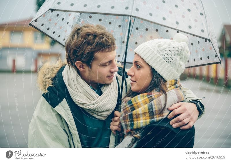 Junges Paar umarmt sich an einem regnerischen Herbsttag unter einem Regenschirm Lifestyle Glück schön Winter Mensch Frau Erwachsene Mann