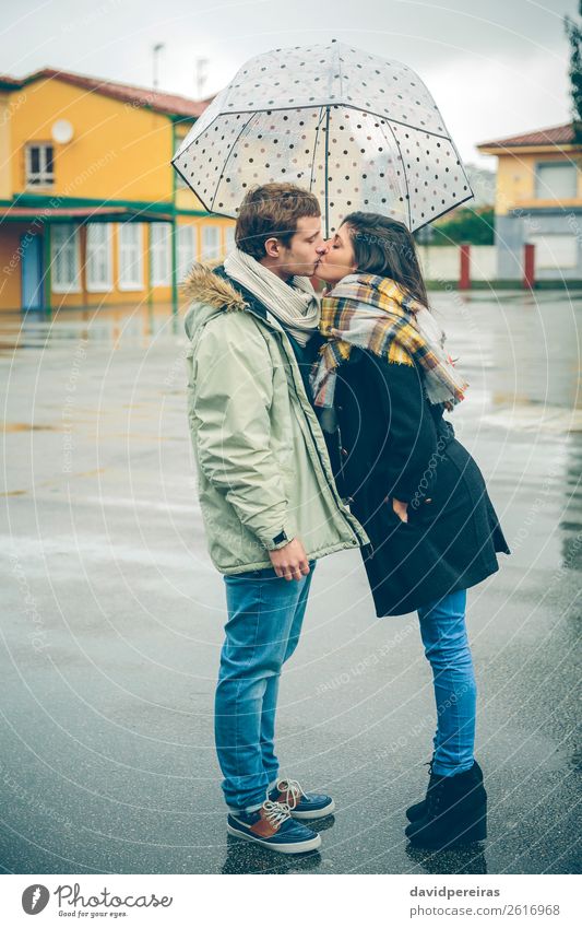 Junges Paar, das sich an einem regnerischen Tag unter dem Regenschirm im Freien küsst. Lifestyle schön Winter Mensch Frau Erwachsene Mann