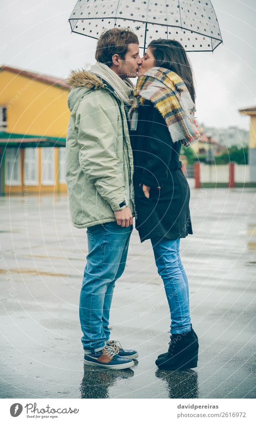 Junges Paar, das sich an einem regnerischen Tag unter dem Regenschirm im Freien küsst. Lifestyle Glück schön Winter Mensch Frau Erwachsene Mann