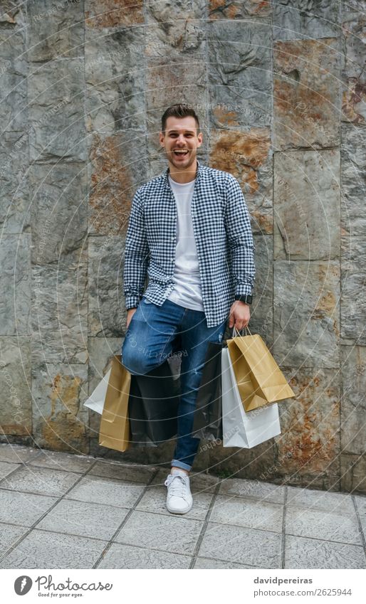 Junger Mann mit Einkaufstaschen Lifestyle kaufen Glück Haare & Frisuren Erholung Freizeit & Hobby Mensch Erwachsene Mode Jeanshose Turnschuh Lächeln lachen