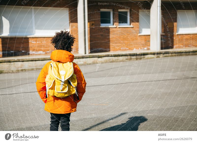 Kleiner Schuljunge am Eingang der Schule Winter Kind Junge Herbst Mantel klein gelb schwarz Schulkind Rucksack Schüler gutaussehend Afrikanisch Nachkomme