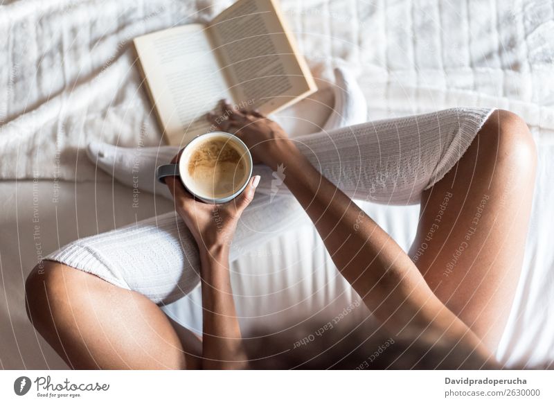 Frau liest ein Buch und trinkt Kaffee auf dem Bett mit Socken. Kniestrümpfe lesen Strumpfhose Beine Mädchen weiß schwarz Lächeln weich Tasse bequem Morgen