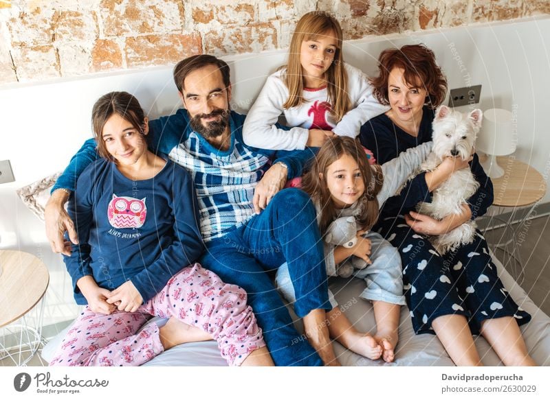 Ein erwachsenes Paar entspannte sich zu Hause im Bett mit ihren vier kleinen Töchtern und dem Hund. Familie & Verwandtschaft 50’s Schlafzimmer Ehefrau Ehemann