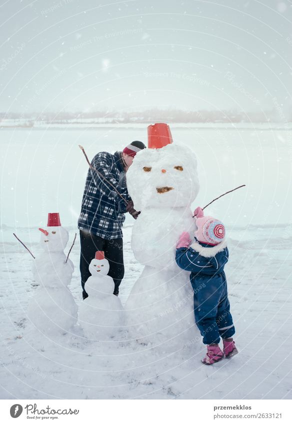 Mann und seine kleine Tochter basteln einen Schneemann, verbringen gemeinsam Zeit im Freien, haben Spaß auf Schnee im Winter Lifestyle Freude Glück