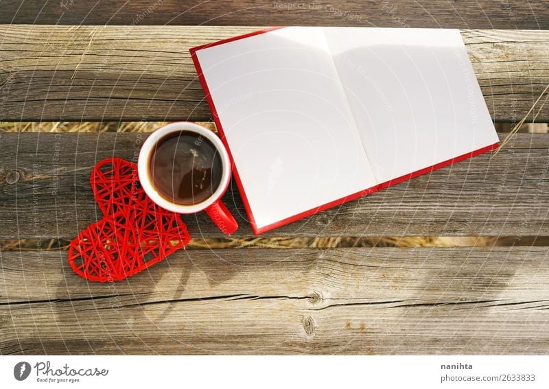Rote Tasse mit Kaffee auf einer Holzbank im Freien am Morgen. Frühstück Getränk Heißgetränk Tee Becher Winter Buch lesen Herbst Wärme Papier Herz frisch
