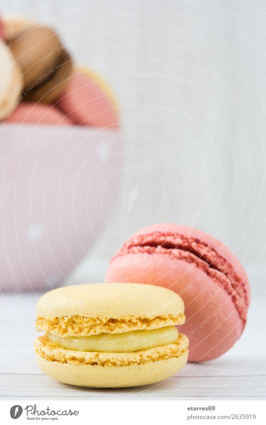 Bunte Makronen auf weißem Holztisch Macaron Erdbeeren Zitrone Dessert Kaffee gelb Schokolade Konfekt Himbeeren Tradition Süßwaren Bonbon Plätzchen ausstechen