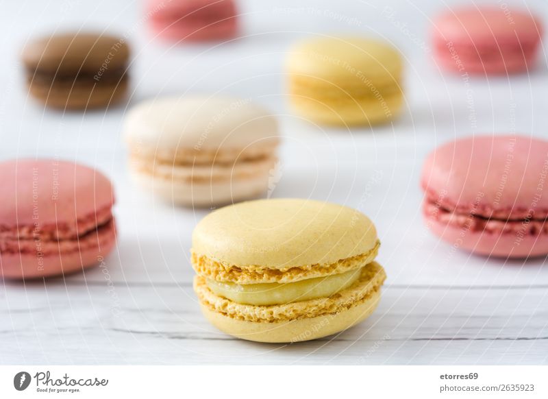 Bunte Makronen auf weißem Holztisch Macaron Erdbeeren Zitrone Dessert Kaffee gelb Schokolade Konfekt Himbeeren Tradition Süßwaren Bonbon Plätzchen ausstechen