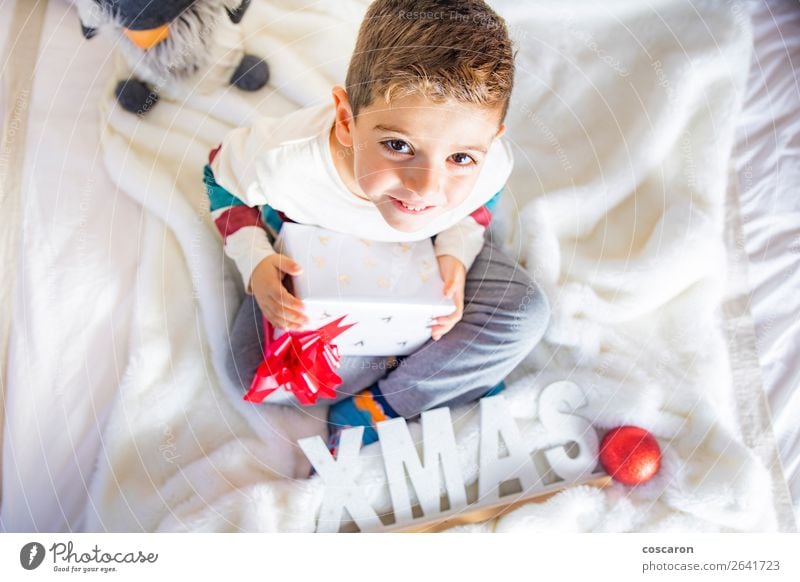 Kleines Kind am Weihnachtstag mit einem Geschenk auf dem Bett Lifestyle Glück Gesicht Winter Haus Dekoration & Verzierung Raum Kinderzimmer Schlafzimmer