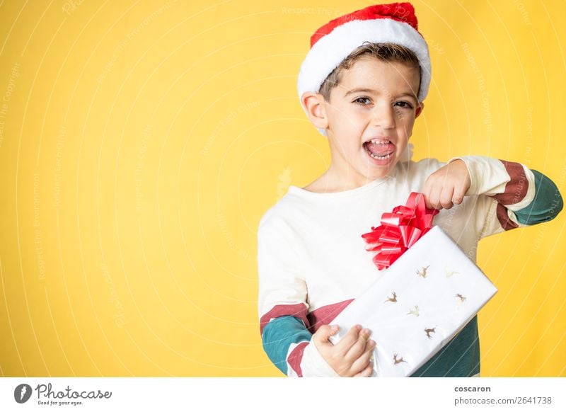 Kleines Kind mit einem Geschenk auf gelbem Hintergrund am Weihnachtstag. Lifestyle Stil Design Freude Glück schön Winter Feste & Feiern Weihnachten & Advent