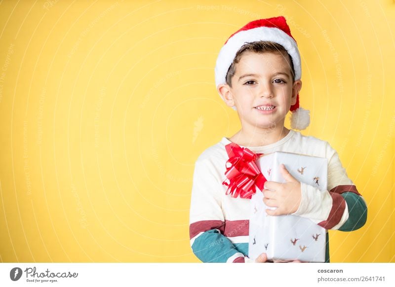 Kleines Kind mit einem Geschenk auf gelbem Hintergrund am Weihnachtstag. Stil Design Freude Glück schön Winter Feste & Feiern Weihnachten & Advent